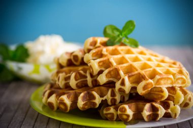 Tatlı süzme peynirli gofretler, bir tutam naneli, mavi arka planda..