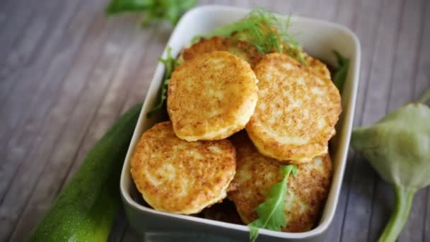 fried vegetable pancakes from squash and zucchini with herbs, on a light wooden table.