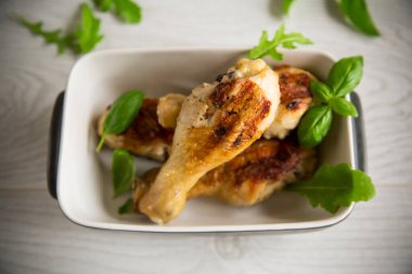 Baharatla kızartılmış tavuk budu ve seramik kasede otlar.