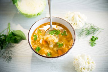 vegetable summer soup with cauliflower in a bowl on a light wooden table