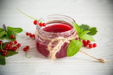 Olgun kırmızı üzümlerden gelen tatlı yaz reçeli ahşap bir masada kavanozda