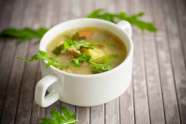 summer light soup with oatmeal and arugula in a plate on the table