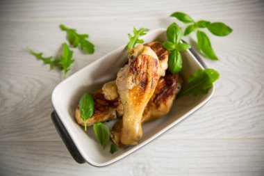 Baharatla kızartılmış tavuk budu ve seramik kasede otlar.