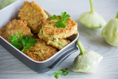 vegetable fried squash and zucchini cutlets in a ceramic form on a light wooden table