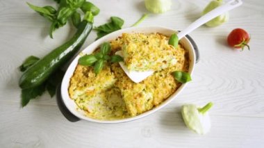 vegetable casserole of patissons, zucchini, carrots in a ceramic form on a light wooden table.