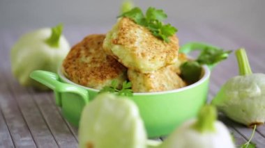 vegetable fried squash and zucchini cutlets in a ceramic form on a light wooden table
