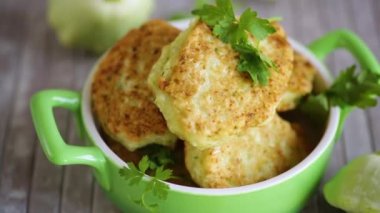 vegetable fried squash and zucchini cutlets in a ceramic form on a light wooden table