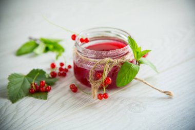 Olgun kırmızı üzümlerden gelen tatlı yaz reçeli ahşap bir masada kavanozda