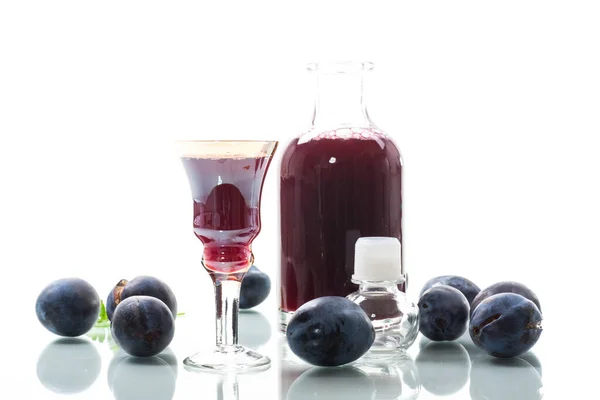 Czerwone Wino Śliwkowe Szklance Karafka Tle Dojrzałych Dużych Śliwek Wyizolowanych — Zdjęcie stockowe