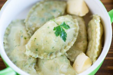 İçi doldurulmuş haşlanmış hamur köfteleri seramik tabakta otlarla dolu..