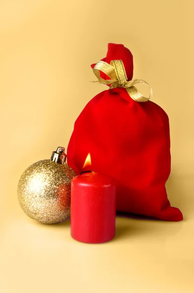 Bolso rojo para regalo con bolas de Navidad de cinta de oro y vela ardiente — Foto de Stock