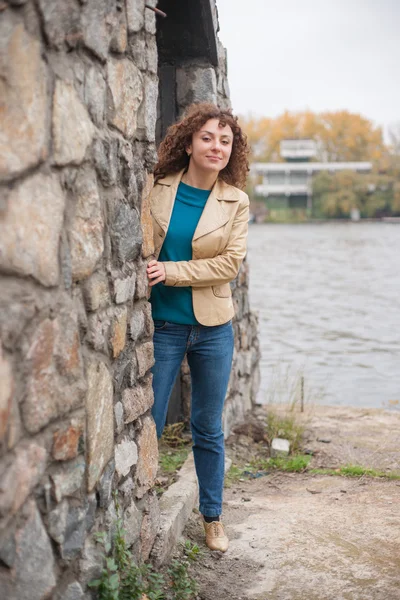 Beautiful sexy brunette girl poses near stone wall — Stock Photo, Image