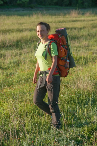 Feliz mulher sorridente no terreno. Grama verde em primeiro plano e céu limpo no fundo . — Fotografia de Stock