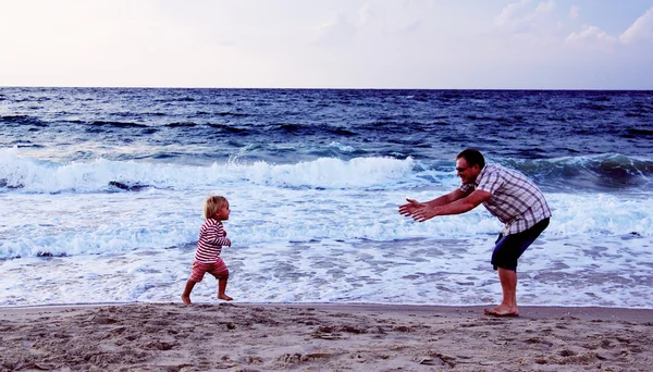 Батько і дочка грають разом на пляжі під час заходу сонця — стокове фото