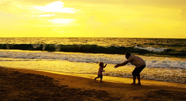 Far och dotter spelar tillsammans på stranden vid solnedgången — Stockfoto