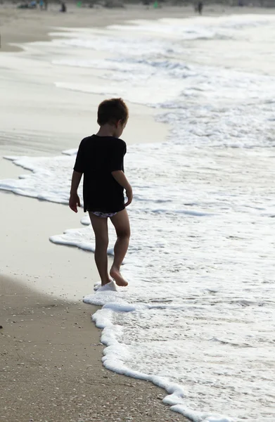 Niño en el mar en los colores del atardecer — Foto de Stock