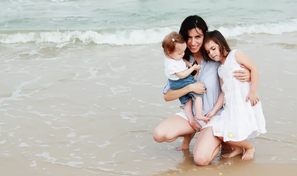 Moeder met twee dochters op het strand — Stockfoto