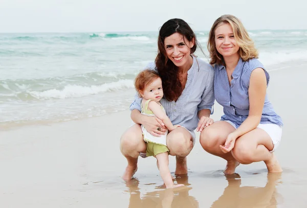 Twee mooie meisjes met een baby op het strand — Stockfoto