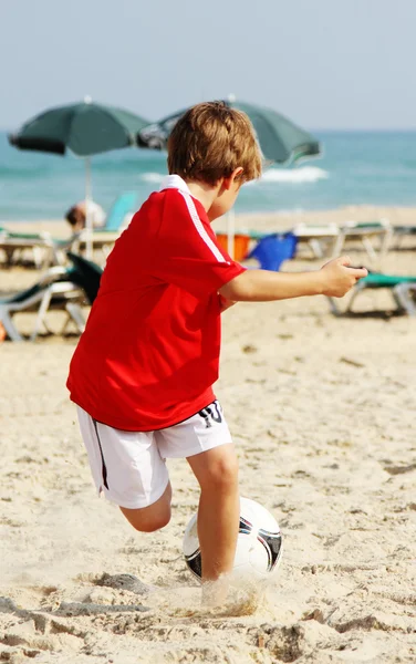 7 years old boy playing football on the beach — Stock Photo, Image