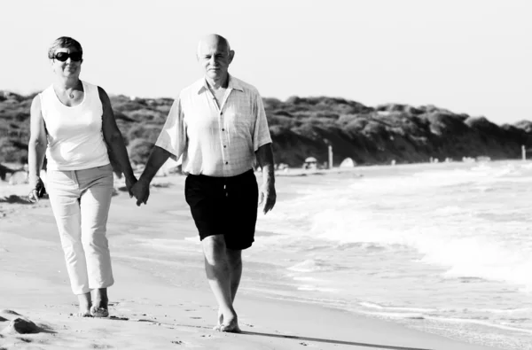 Felice coppia anziana che cammina insieme su una spiaggia — Foto Stock
