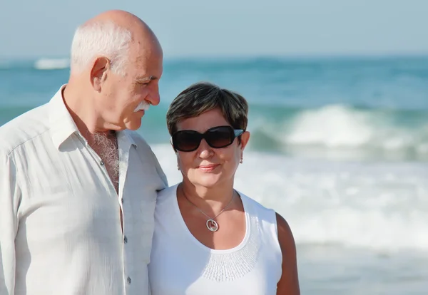 Happy senior couple walking together on a beach — Stock Photo, Image