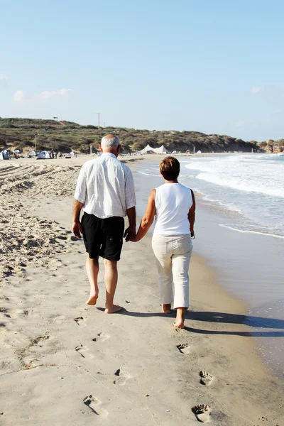 Пожилая пара, гуляющая вместе по пляжу — стоковое фото