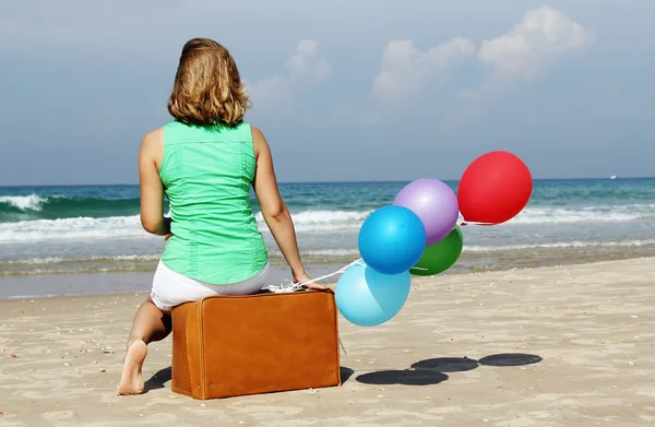 Bella ragazza seduta su valigia vintage sulla spiaggia — Foto Stock