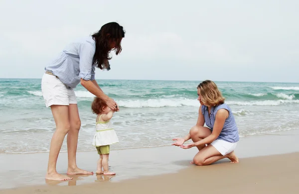 Twee mooie meisjes met een baby op het strand — Stockfoto