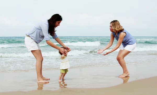 Twee mooie meisjes met een baby op het strand — Stockfoto