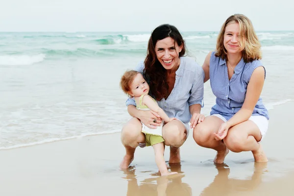 Två vackra kvinnor med en baby på stranden — Stockfoto