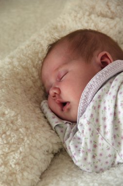 Aylık çocuk beyaz bir battaniyeye uzanıyor.