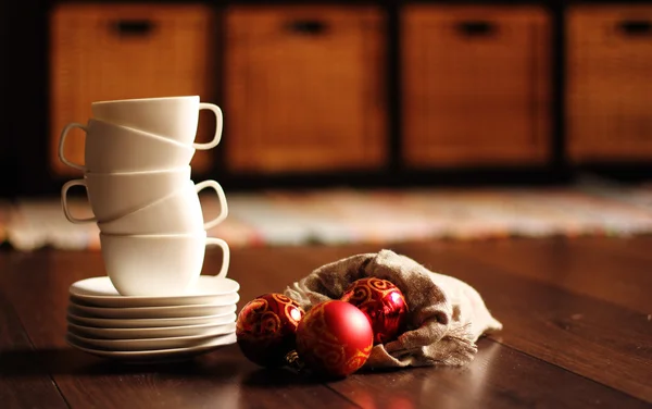 Weiße Tassen und rote Weihnachtskugeln. Weicher Fokus — Stockfoto