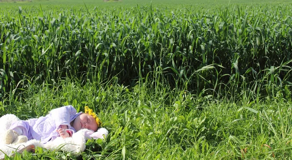 Miesięczna dziewczynka leżąca na trawie obok czerwonych maków — Zdjęcie stockowe