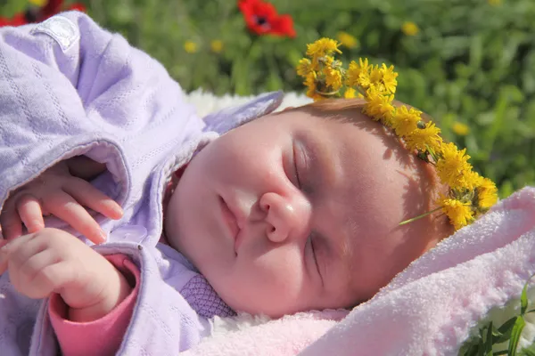 Kırmızı gelinciklerin yanındaki çimlerde yatan bir aylık kız. — Stok fotoğraf