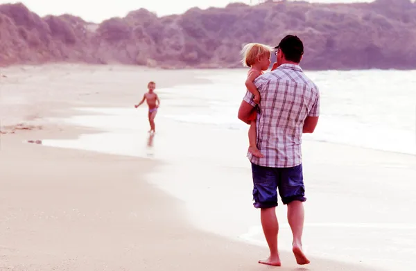 Father with two kids on vacation at sea on sunset colours — Stock Photo, Image