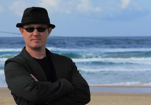 En man i en hatt och solglasögon på havet — Stockfoto