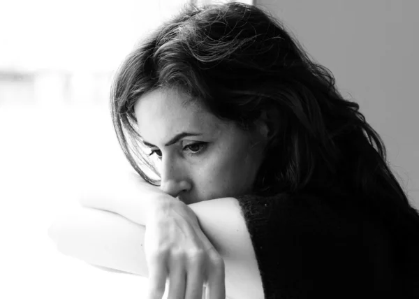 Beautiful 35 year old woman stands in front of the window — Stock Photo, Image