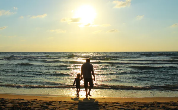Vader en zoon op zee kijken naar de zonsondergang — Stockfoto