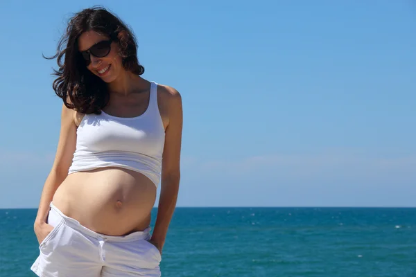 Pregnant young woman against the blue sea Royalty Free Stock Photos