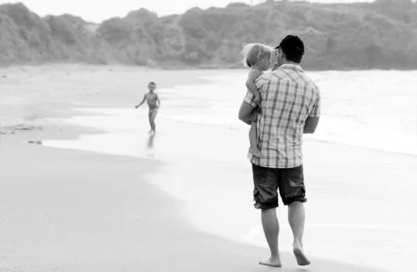 Père avec deux enfants en vacances en mer sur les couleurs du coucher du soleil — Photo