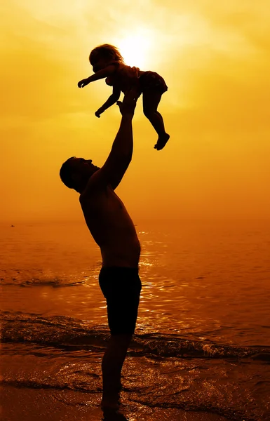 父亲和女儿一起在海滩上玩在日落时 — 图库照片