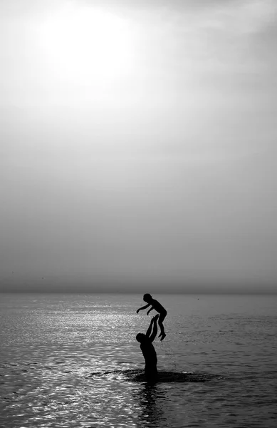 Pai e filho no mar ao pôr do sol — Fotografia de Stock