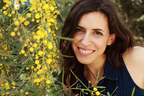Sarı çiçekli dışarıda gülümseyen kadın portresi — Stok fotoğraf