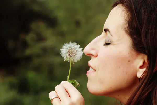 Portret jonge vrouw waait paardebloem — Stockfoto