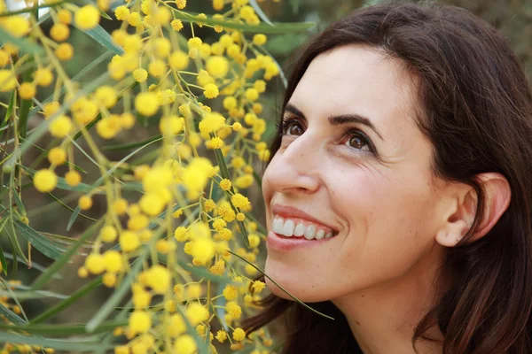 Retrato de mulher sorridente ao ar livre com flores amarelas — Fotografia de Stock