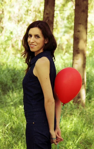 Mooie vrouw met rode ballon in het park — Stockfoto