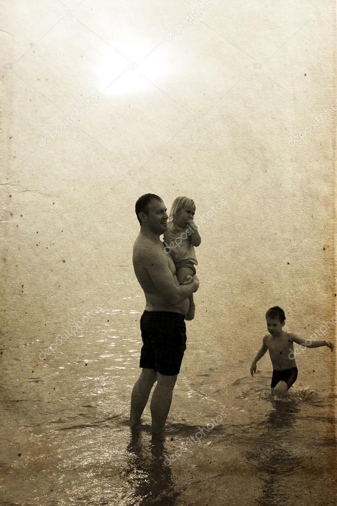 Father and two kids on the beach at sunset. Photo in old image s