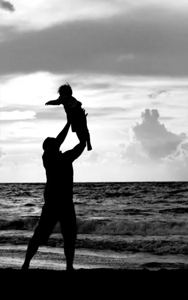 Pai e filha brincando juntos na praia ao pôr do sol — Fotografia de Stock