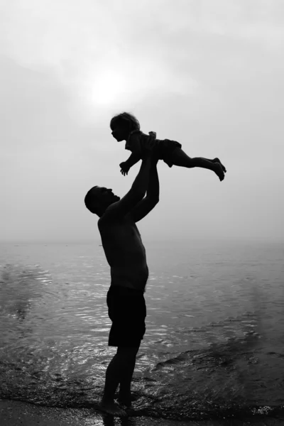 Far och dotter spelar på stranden vid solnedgången — Stockfoto