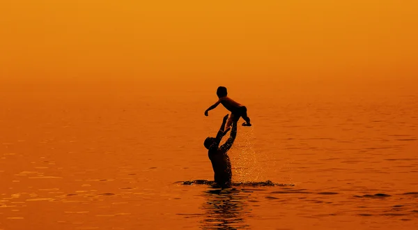 Father and son swimming in the sea at sunset — Stock Photo, Image